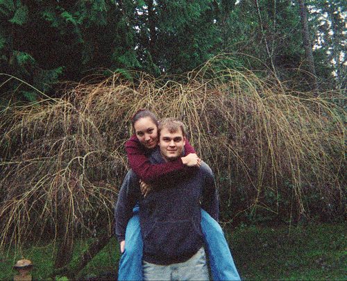 Raichelle riding piggyback on Michael in evergreen woods